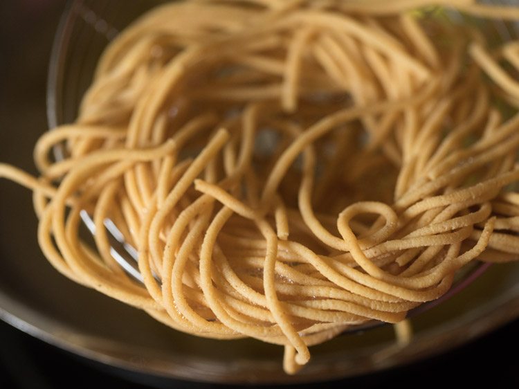 removing fried omapodi from the oil using a slotted spoon. 