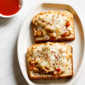 paneer toast served on a white platter with a small bowl of tomato ketchup kept on the top left side and text layovers.