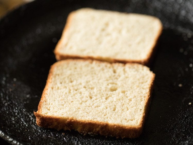 2 bread slices kept on a heavy pan brushed with some butter. 