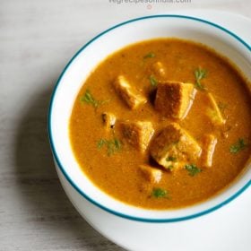 paneer gassi served in a light blue rimmed white bowl with text layovers.