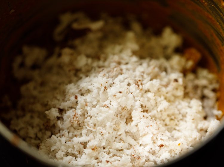 tightly packed fresh grated coconut and water added to the grinder jar for paneer gassi recipe. 