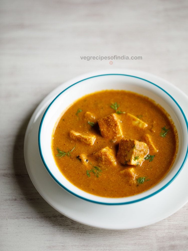 paneer gassi served in a light blue rimmed white bowl with text layover. 