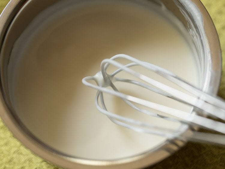 whisking fresh curd in a bowl till smooth. 