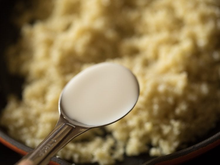 adding milk to the pan with mawa, sugar, and cardamom