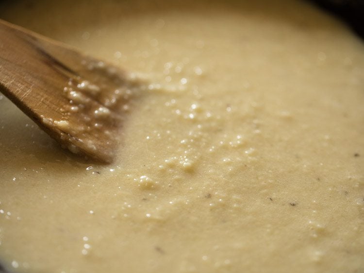 stirring milk peda mixture with a wooden spatula