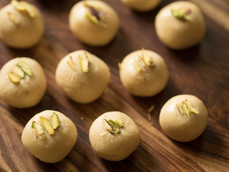 pistachio slivers on peda balls or spheres kept on wooden tray