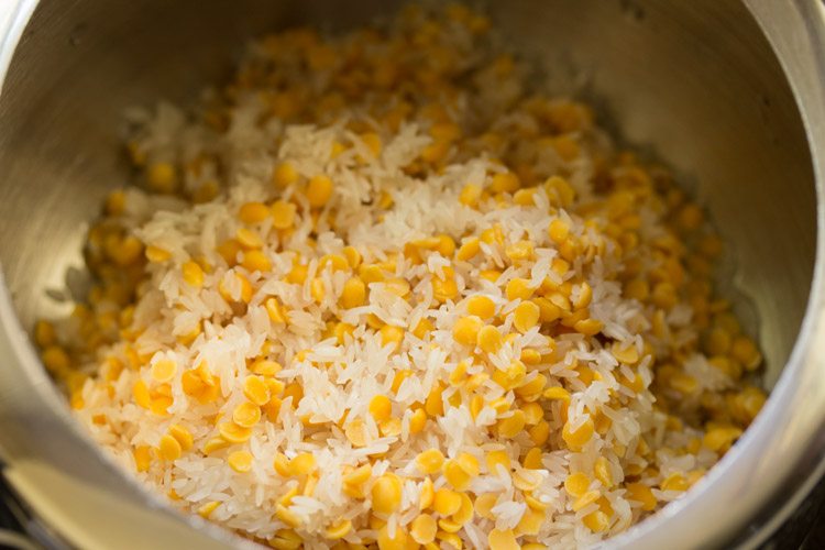 rinsed and drained rice and tuvar dal added in a pressure cooker for sambar sadam. 