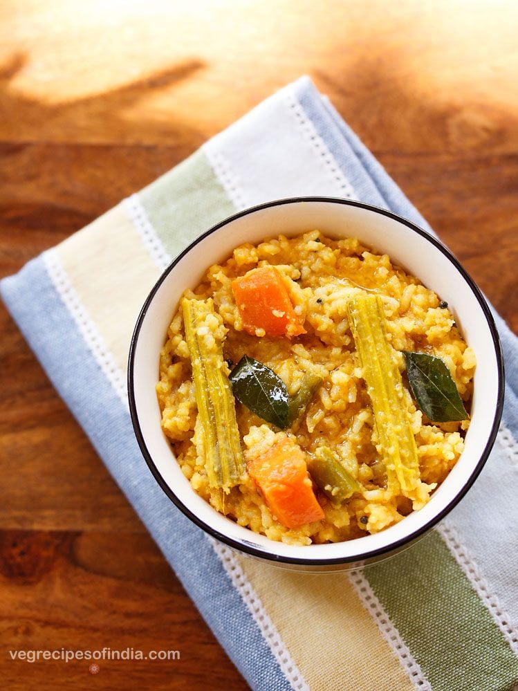 top shot of sambar rice served in a black rimmed ceramic bowl with text layover. 