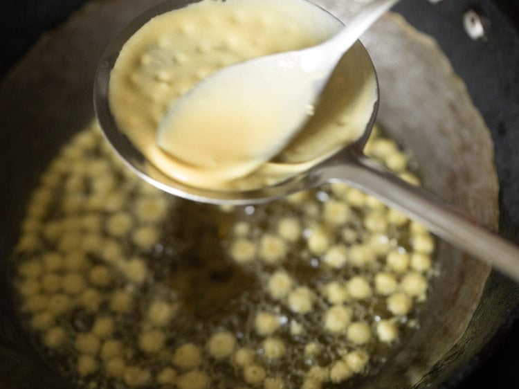 spreading batter on perforated ladle above hot oil. 