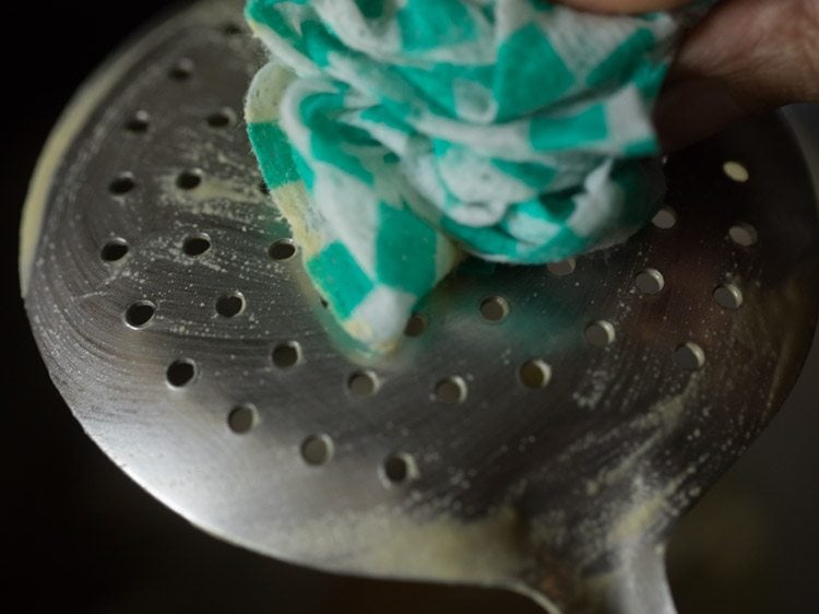 wiping perforated ladle with a thin moist cotton kitchen towel. 