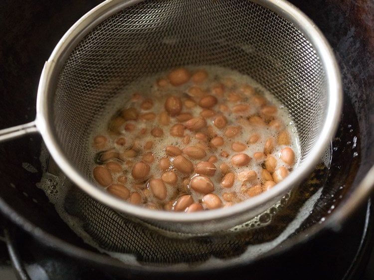 peanuts added in the fine sieve ladle and immersed in hot oil to fry. 