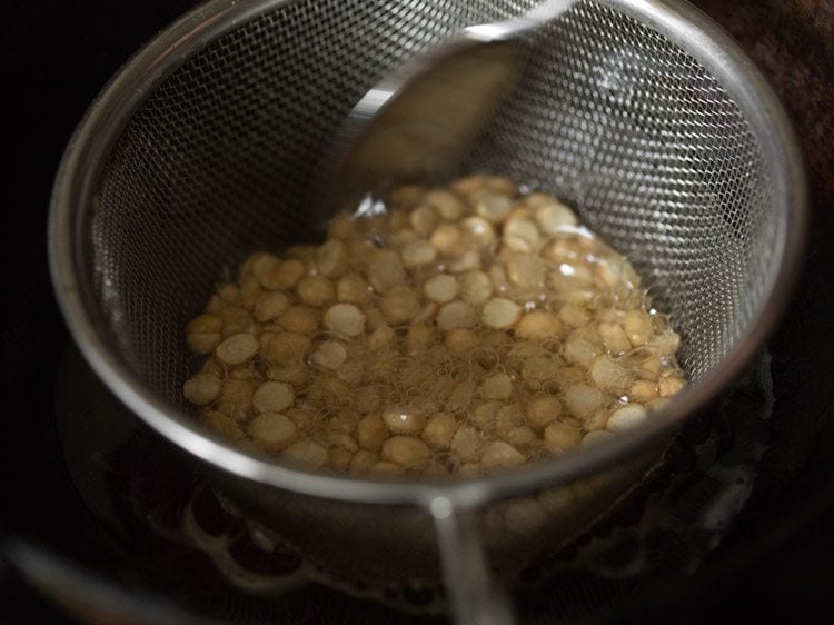 frying roasted chana dal in the sieve ladle till crisp. 
