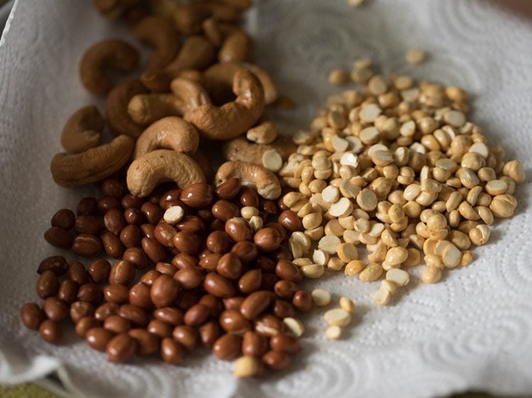 fried chana dal kept with fried cashews and fried peanuts on kitchen paper towels. 