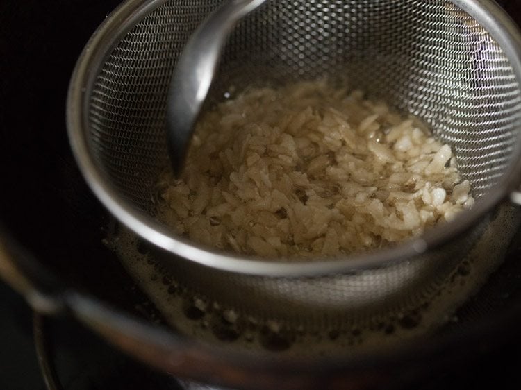 frying poha in sieve ladle till crisp and pale golden. 