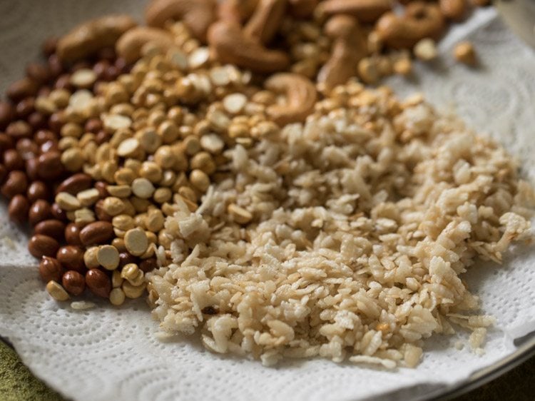 fried poha kept with fried chana dal, fried cashews and fried peanuts on kitchen paper towels. 