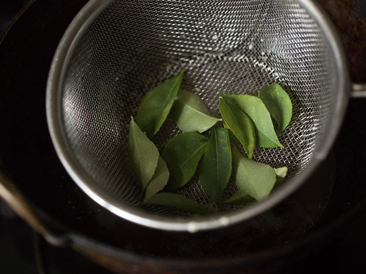 curry leaves added to fine sieve ladle to fry. 