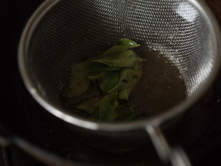 frying curry leaves in sieve ladle till crisp. 