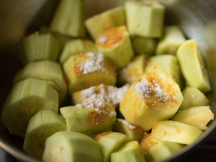 turmeric powder and salt added to pointed gourd pieces for making aloo potoler dalna. 