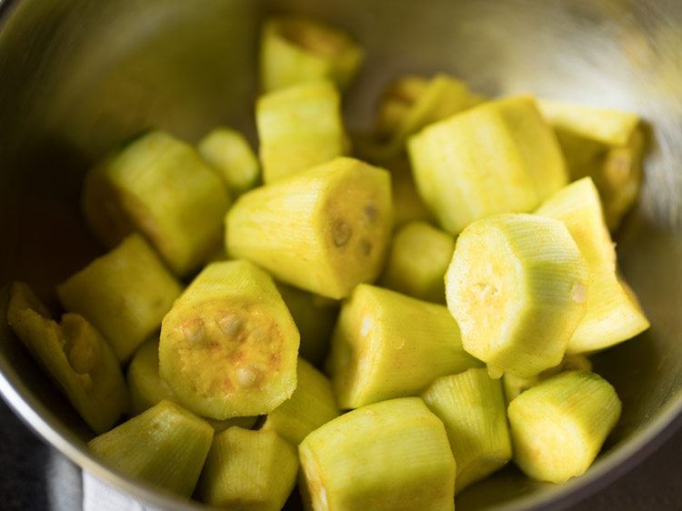 turmeric powder and salt mixed well with the pointed gourd pieces for making aloo potoler dalna. 