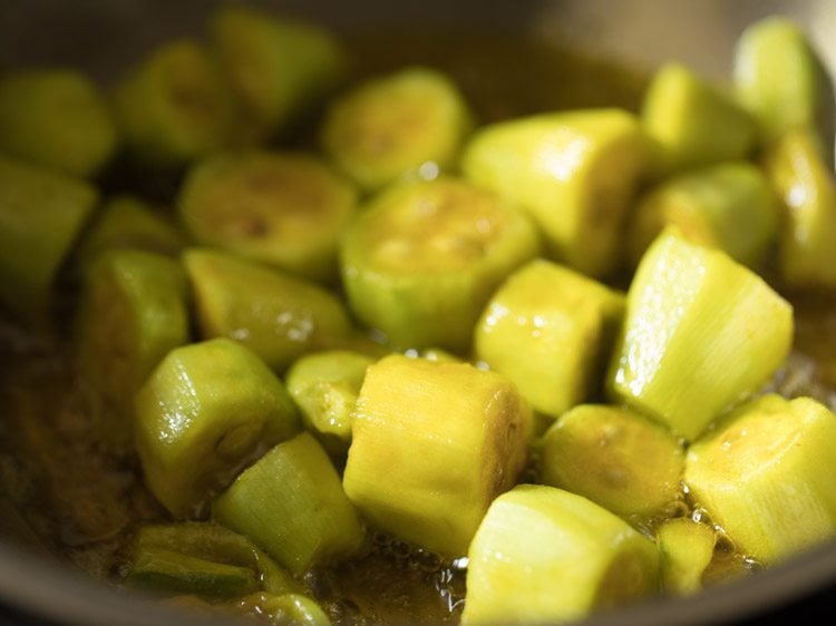 frying pointed gourd pieces for aloo potol recipe. 