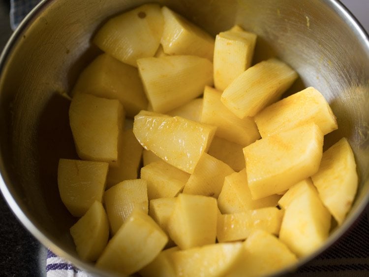 turmeric powder and salt mixed with peeled and chopped potato cubes. 