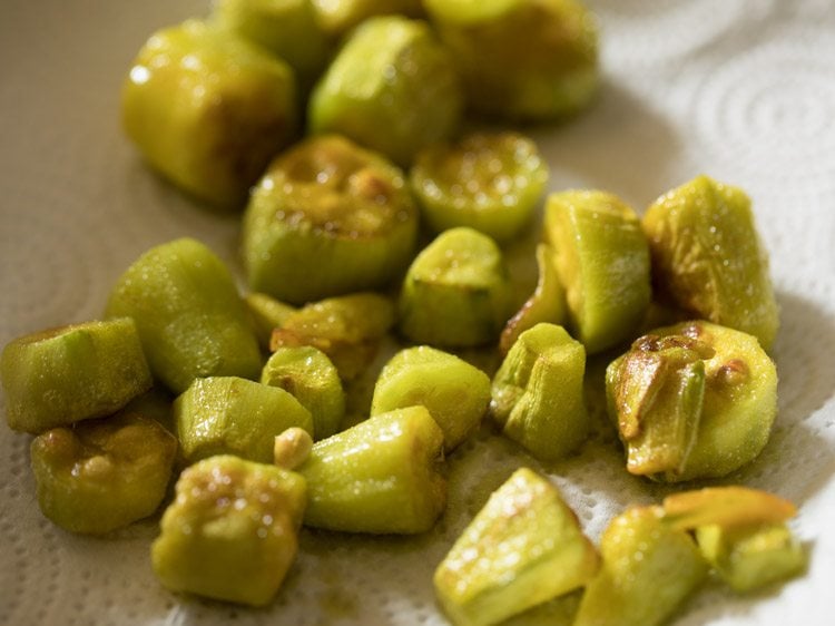 fried pointed gourd pieces placed on kitchen paper towel. 