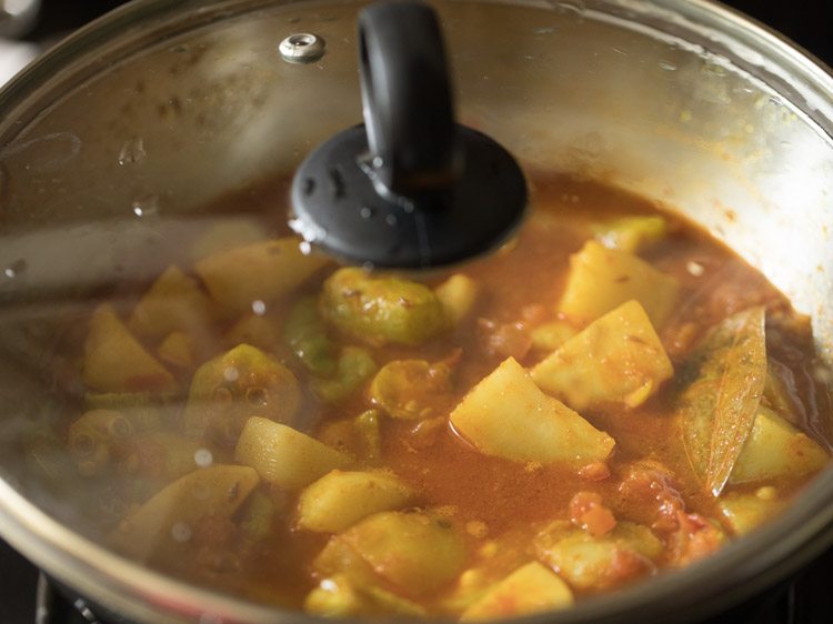simmering aloo potol recipe in a covered pan. 