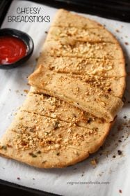 cheesy breadsticks on parchment paper with text layovers.