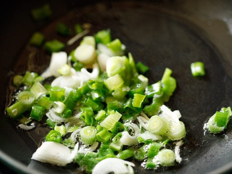 chopped spring onions added to hot oil in wok. 