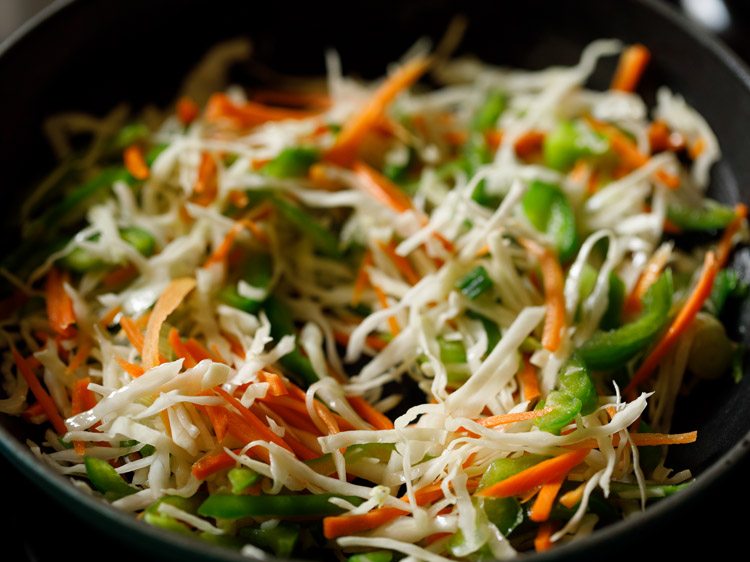 shredded cabbage, shredded carrots and sliced capsicum added to wok. 