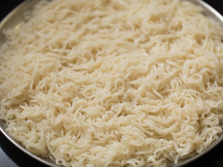 cooked noodles spread on a plate and kept for cooling. 