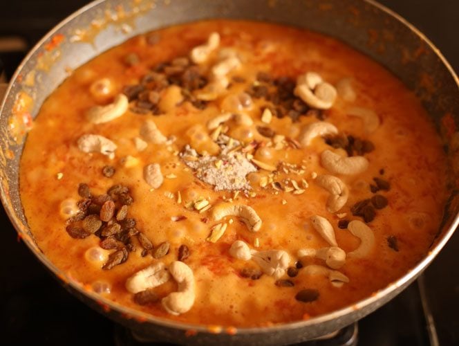 dry fruits and cardamom powder on carrot halwa mixture in pan