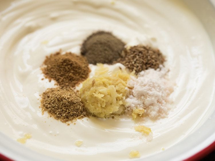 ginger-garlic paste, carom seeds, black pepper powder, coriander powder, garam masala powder and crushed dried fenugreek leaves added to the hung curd-cream mixture. 