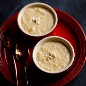 nolen gurer payesh garnished with chopped cashews served in 2 bowls with 2 spoons kept on the left side and text layovers.