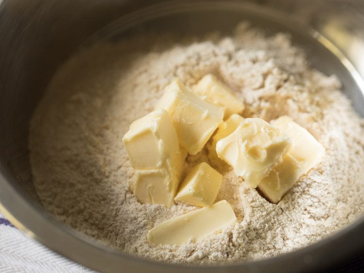 whole wheat flour and cold butter cubes taken in a steel mixing bowl.