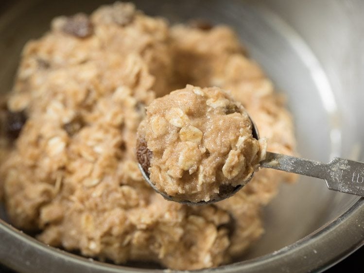 scooping oatmeal raisin cookie dough with a tablespoon.