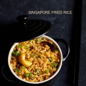 singapore fried rice in a small black pan with lid partially closed.