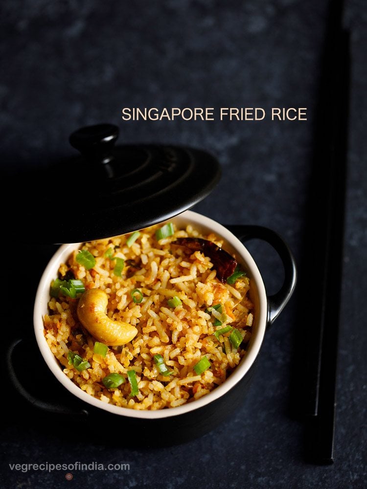 singapore fried rice in a small black pan with lid partially closed.