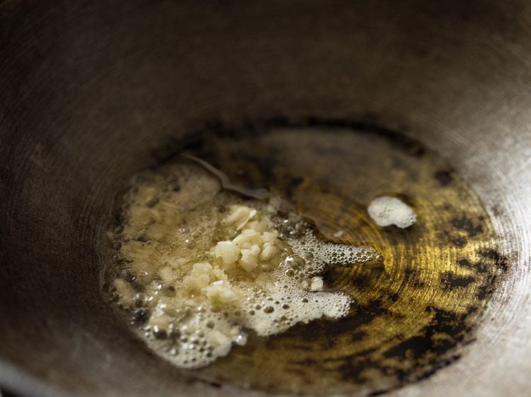 Chopped garlic added to oil in a pan.