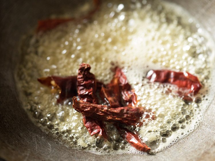 Chopped garlic and red chili added to oil in a pan.