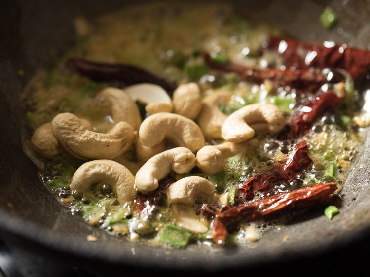 Cashew nuts added to the frying chili and spring onion.