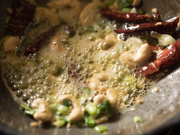 Cashew nuts, chili, and spring onions frying.