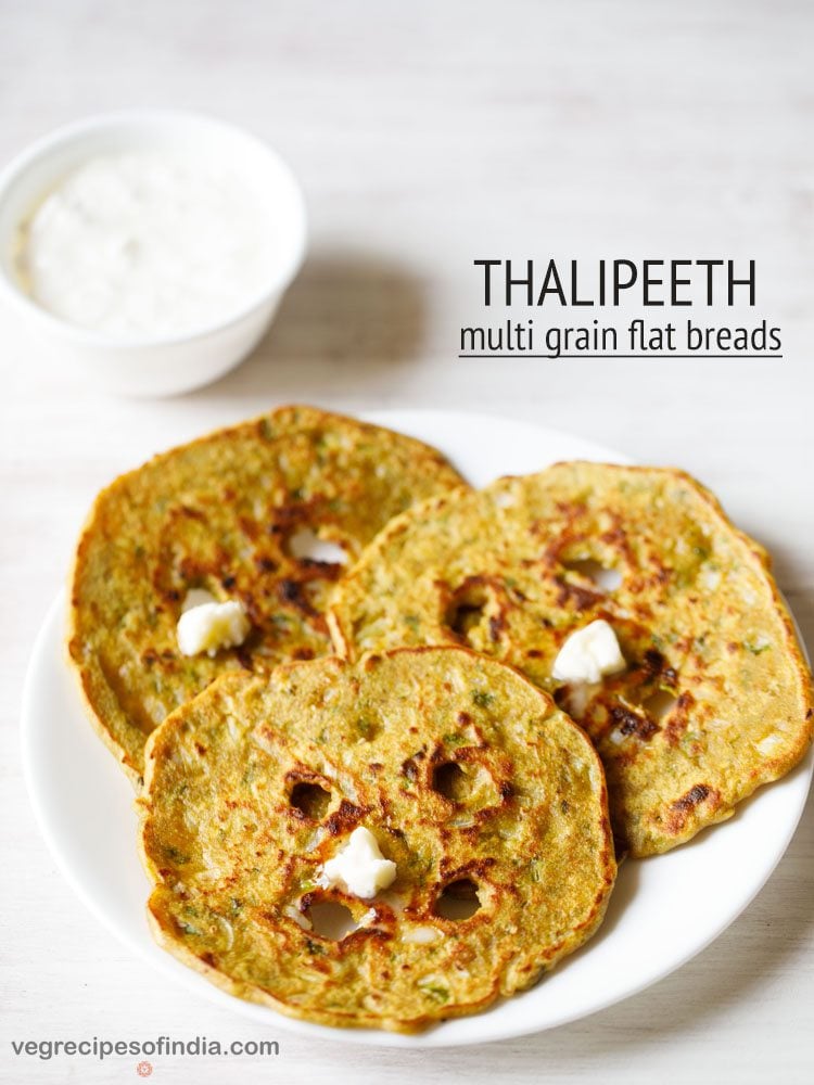 thalipeeth topped with white butter and served on a white plate with a bowl of curd kept on the top left side and text layovers.