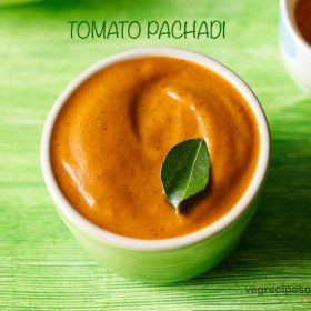 tomato pachadi garnished with a curry leaf, served in a light green colored small bowl with text layovers.