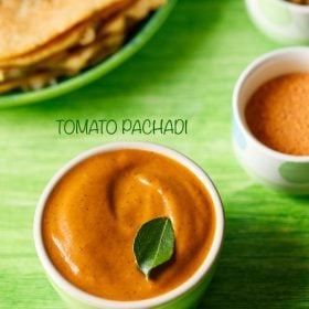 tomato pachadi garnished with a curry leaf, served in a light green colored small bowl with dosas kept on a light green colored platter and text layovers.