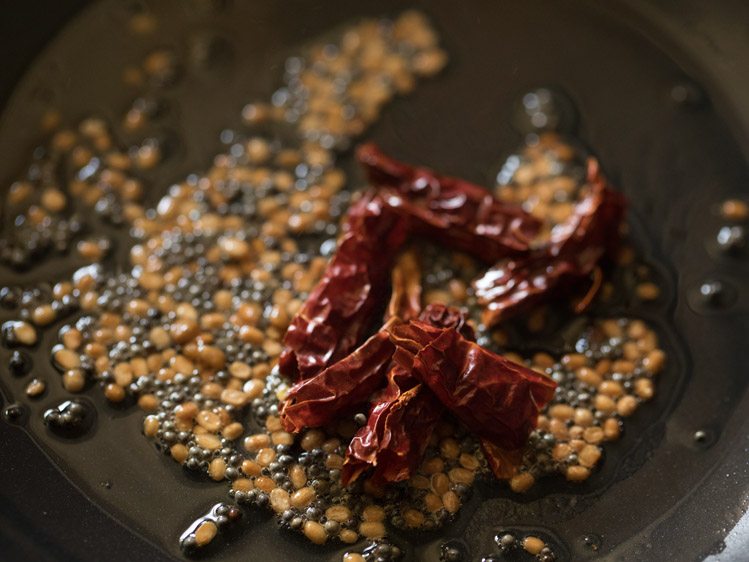 dried red chilies and fenugreek seeds added to the pan for making thakkali pachadi. 