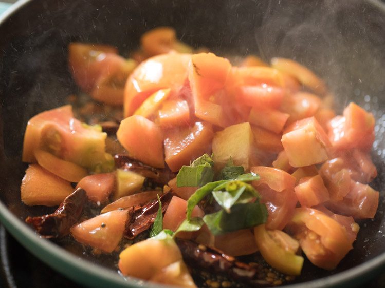 chopped tomatoes and curry leaves added to the spices in the pan for making thakkali pachadi. 