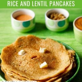 adai stacked and served on a green plate with butter cubes on top and bowls of chutney and sambar kept in the background and text layovers.