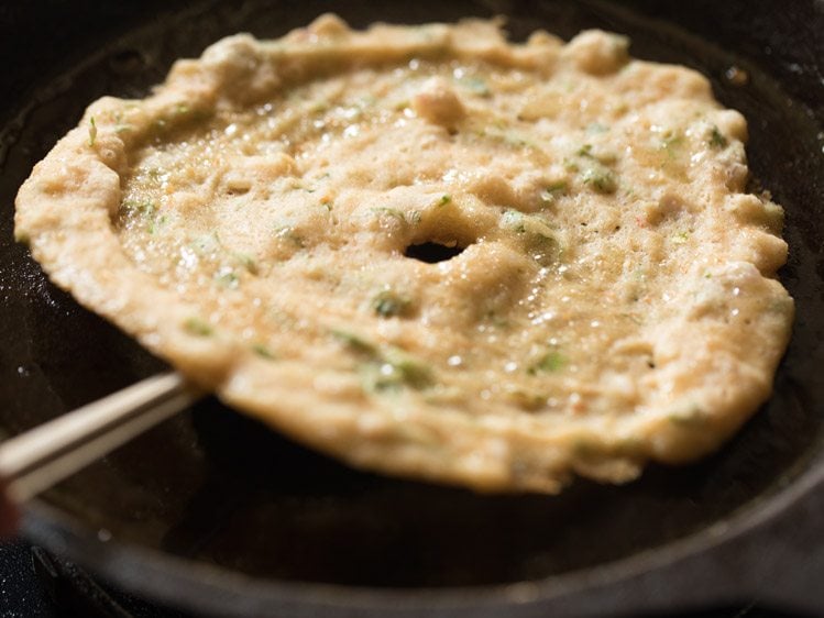 flipping dosa with a spatula. 