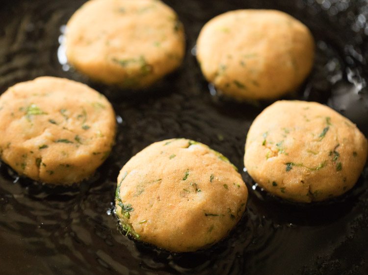 aloo tikkis kept on hot oil on a pan. 